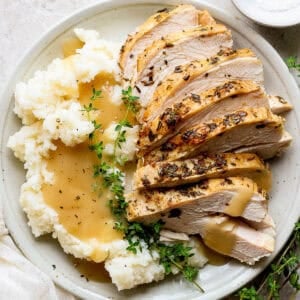 Plate of sliced Instant Pot Turkey Breast, mashed potatoes and gravy.