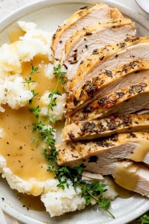 Plate of sliced Instant Pot Turkey Breast, mashed potatoes and gravy.