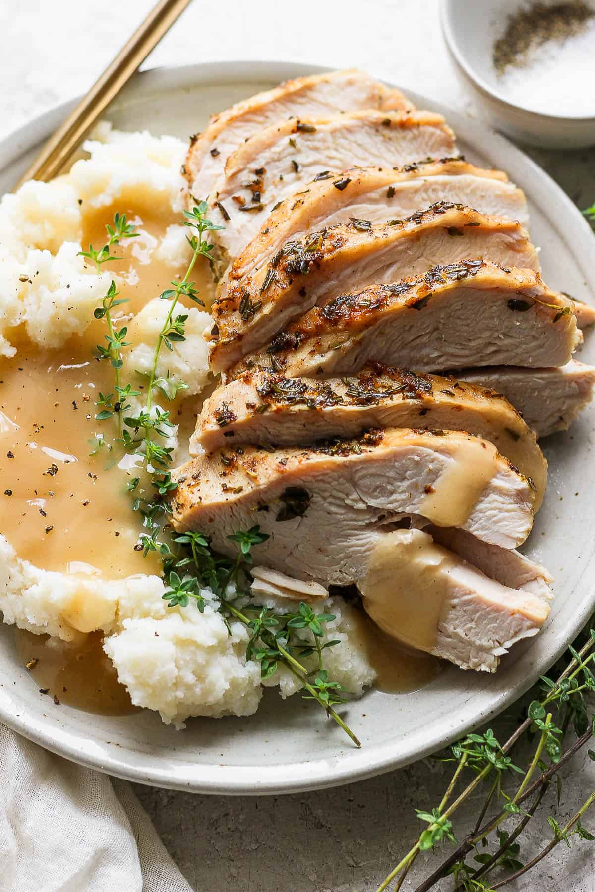 Slices of an Instant Pot turkey breast on a plate with mashed potatoes and gravy.