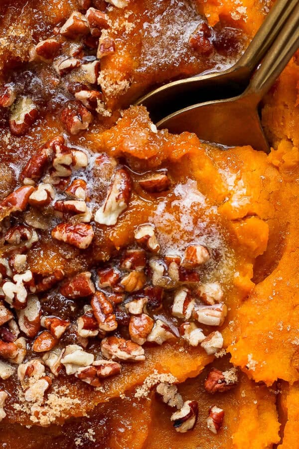 Top down close up shot of a squash casserole with pecans, brown sugar and a spoon sticking out.