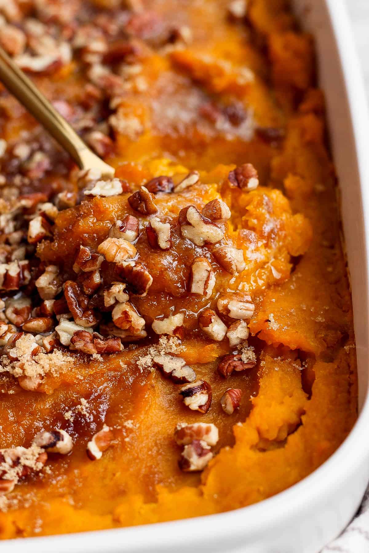 Baked butternut casserole in a casserole dish topped with pecans.