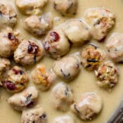 Top down shot of a cast iron skillet filled with gravy and cranberry wild rice thanksgiving meatballs.