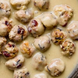 Top down shot of a cast iron skillet filled with gravy and cranberry wild rice thanksgiving meatballs.