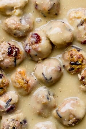 Top down shot of a cast iron skillet filled with gravy and cranberry wild rice thanksgiving meatballs.