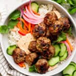 A Banh Mi Rice Bowl with rice, pork meatballs, pickled vegetables, cucumbers and spicy mayo.