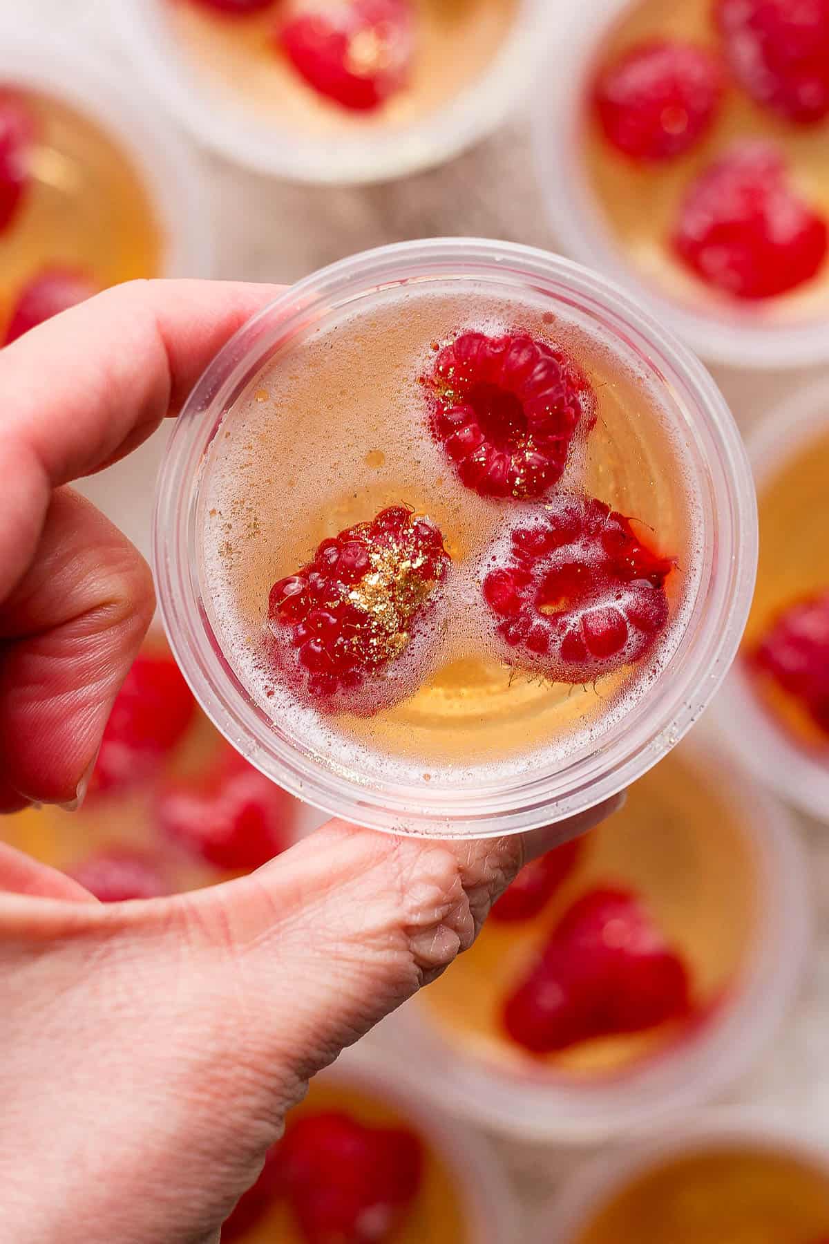 A hand holding a champagne jello shot.