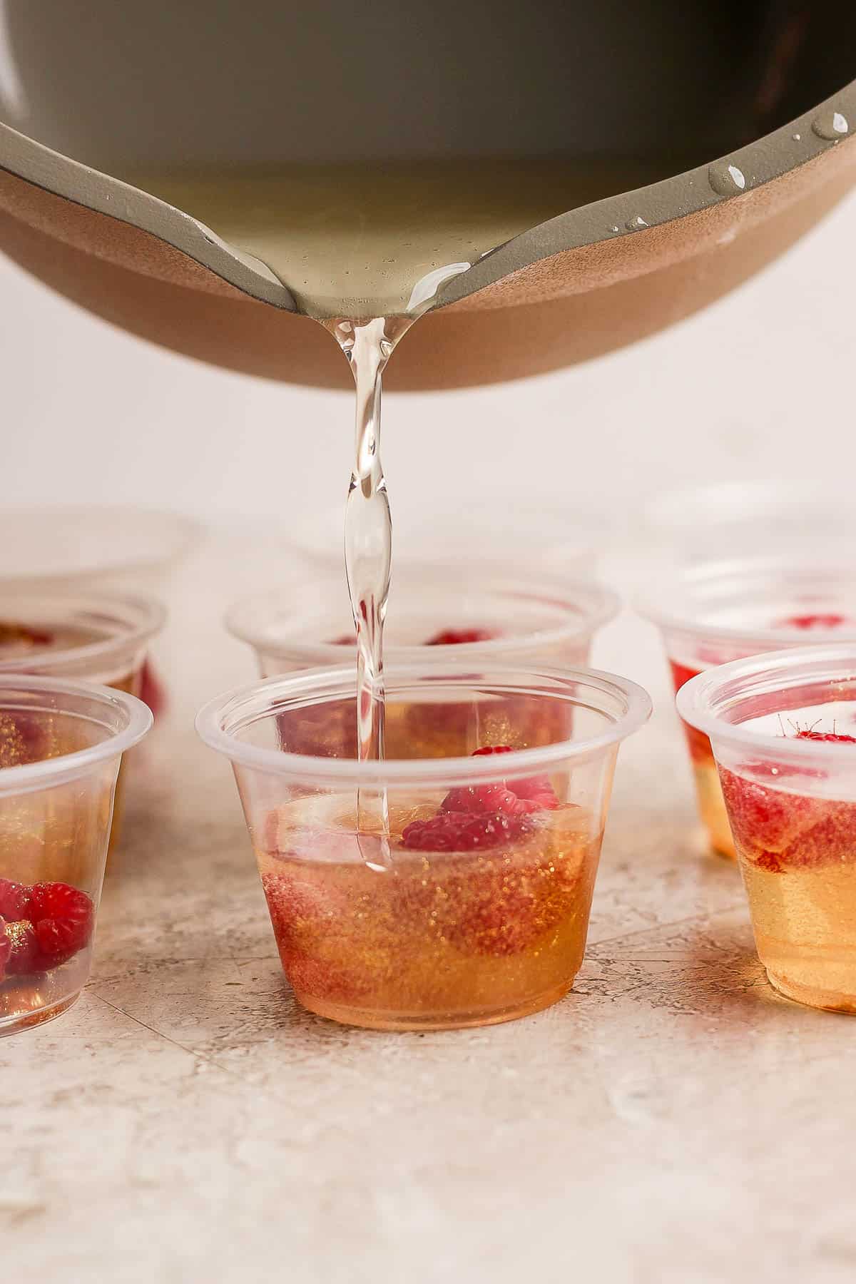 The gelatin mixture being poured into the prepared portion cups.