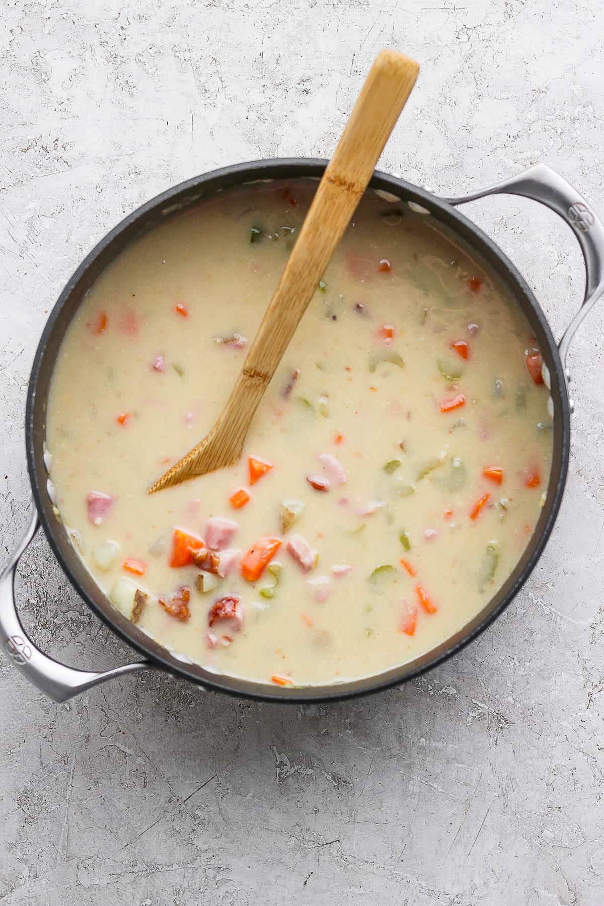 The dutch oven with broth, milk, cream, ham, and seasonings added.