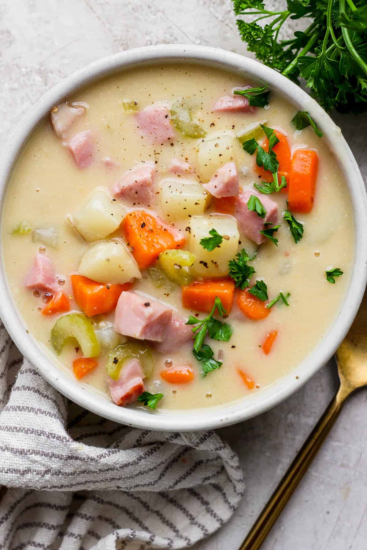 A bowl of ham potato soup with parsley on top.