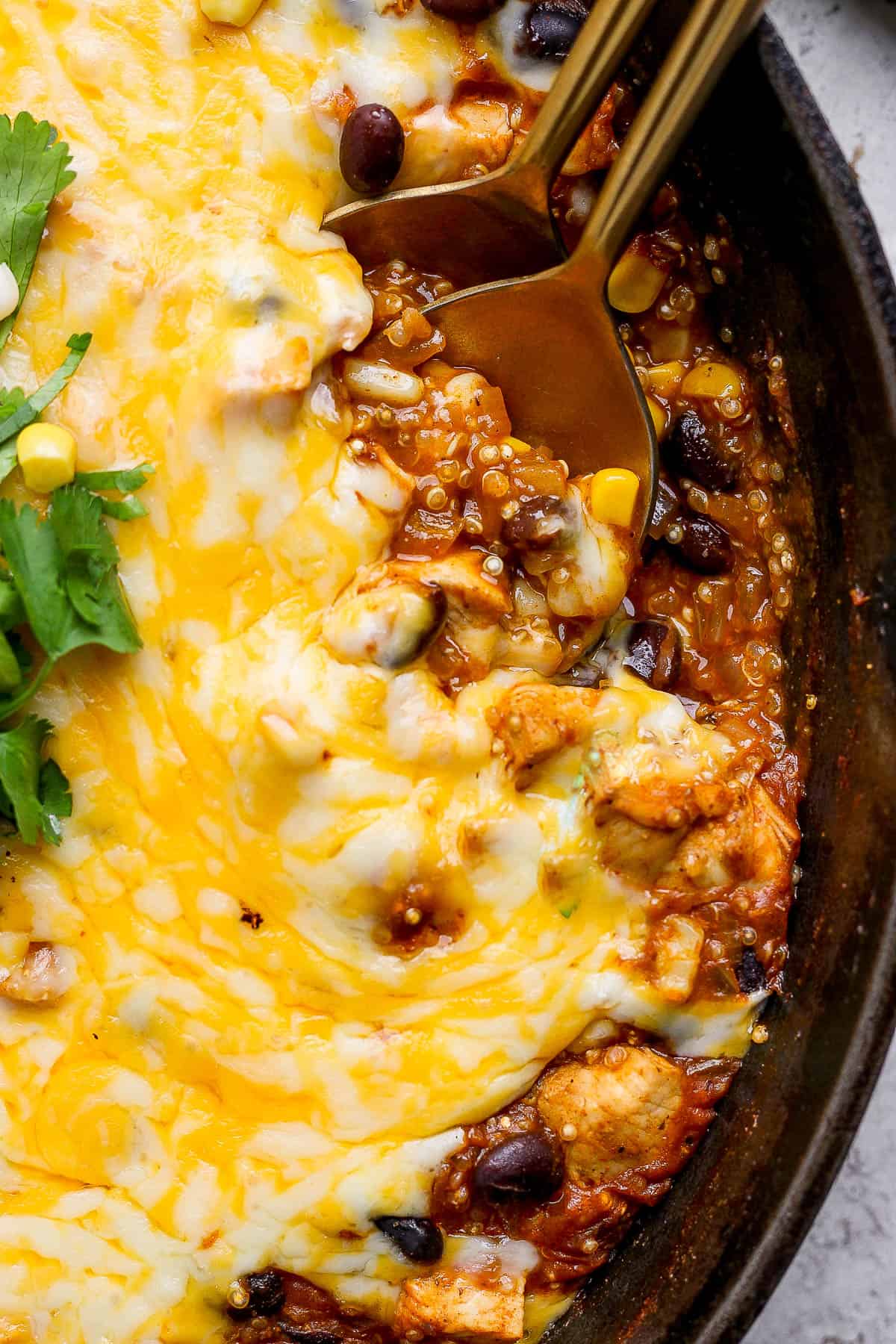 A close up of a spoon in the quinoa enchilada skillet.