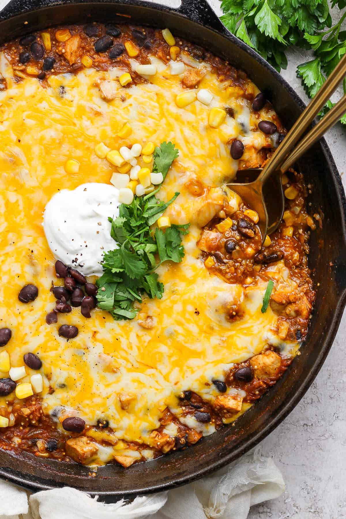 Quinoa enchilada bake in a cast iron skillet topped with sour cream and fresh cilantro.