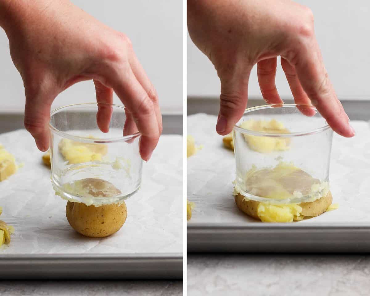 Cooked potatoes on a baking sheet and being smashed with a small glass.
