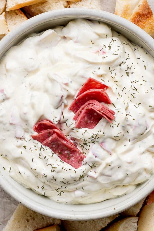 A bowl of homemade bagel dip with cut up pieces of bagel around it.