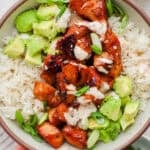 Bowl of bang bang chicken over rice with avocado and bang bang sauce.