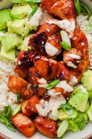 Bowl of bang bang chicken over rice with avocado and bang bang sauce.