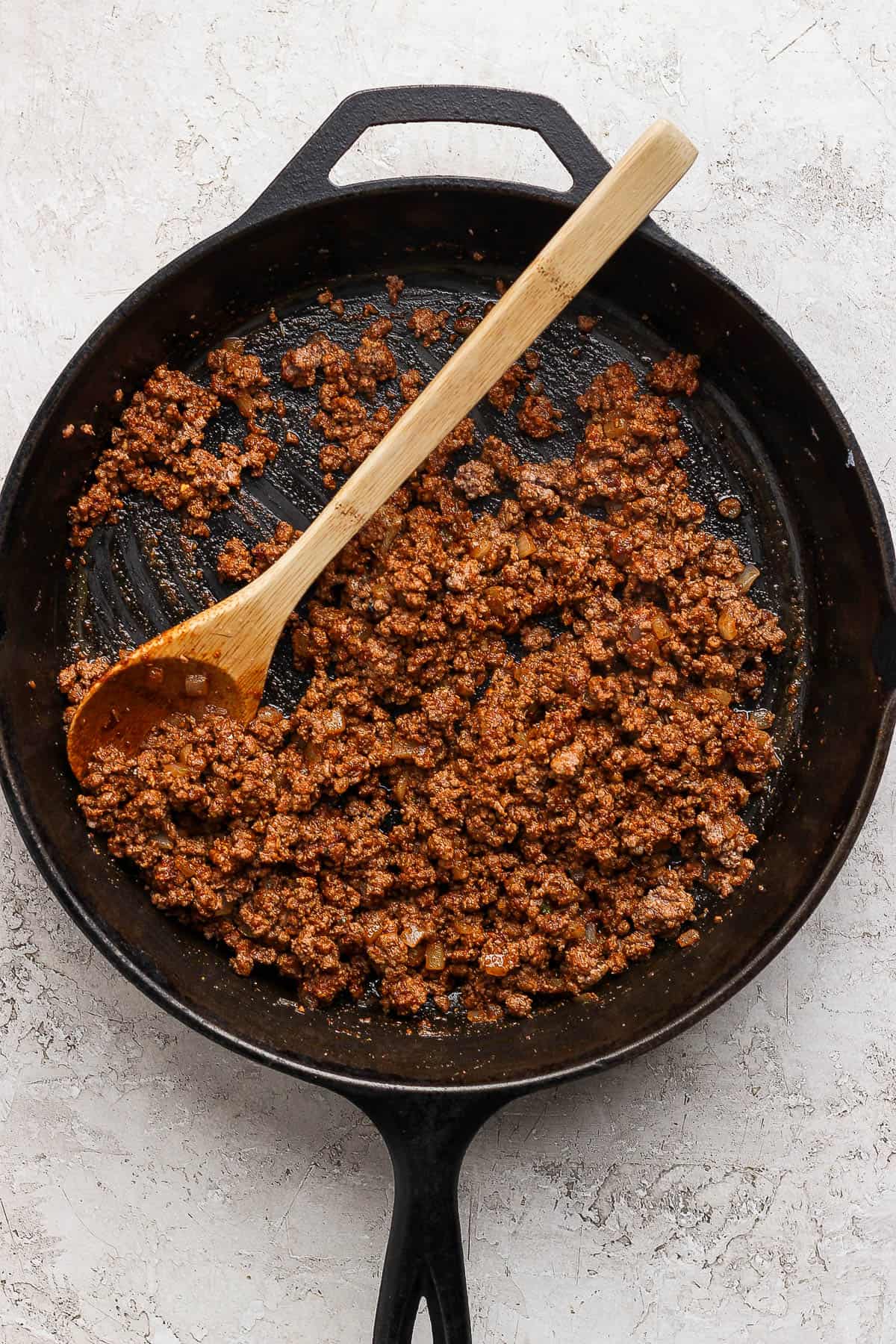 Cooked and seasoned ground beef in a cast iron skillet.