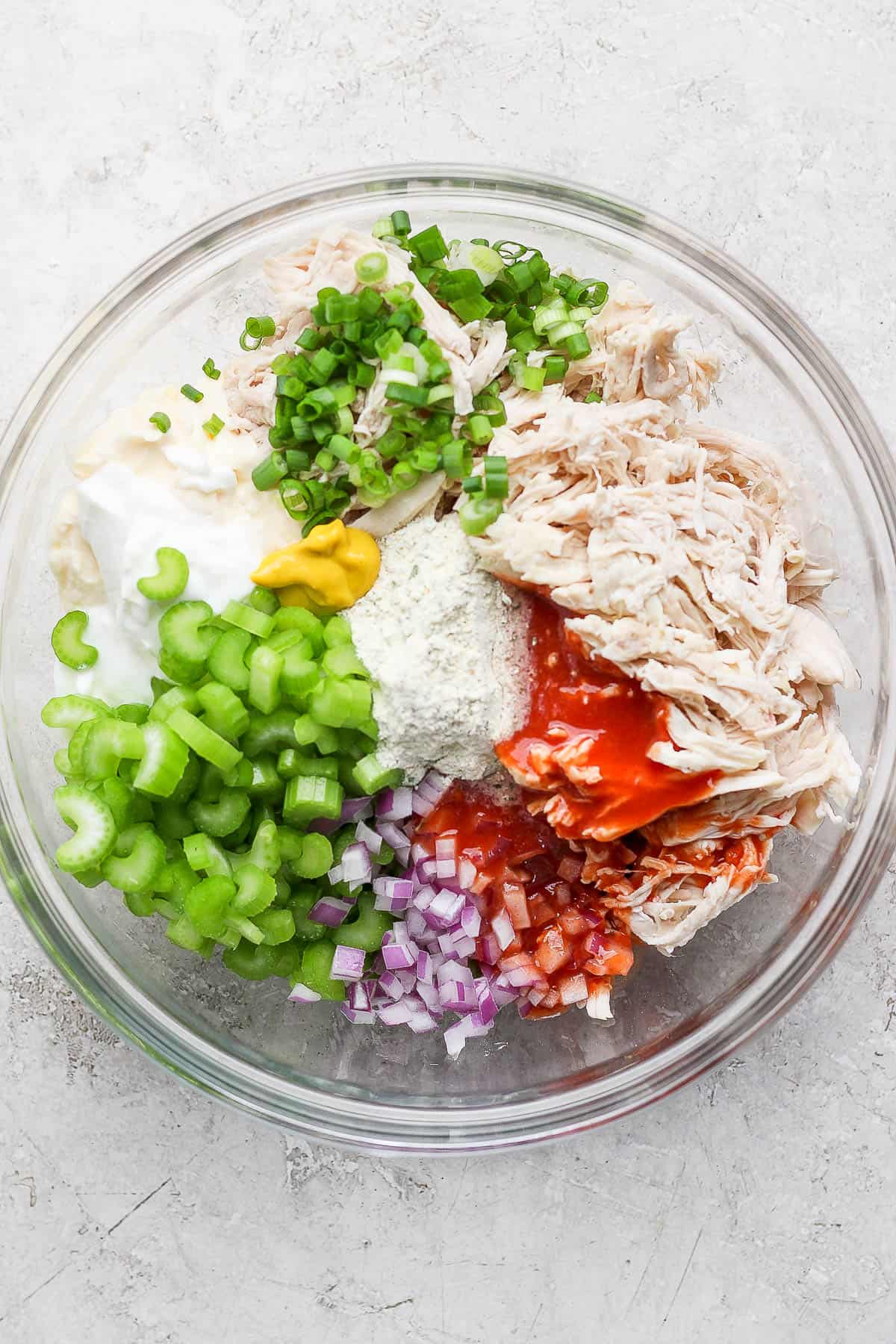 Buffalo ranch chicken salad ingredients separated in a glass blow.