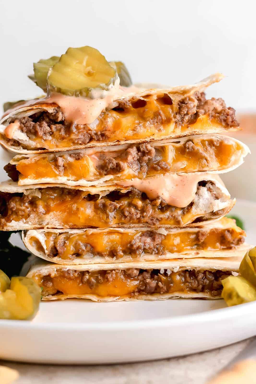 5 pieces of Cheeseburger quesadilla stacked on top of each other on a plate.