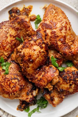 A plate filled with chicken shawarma chicken thighs and fresh parsley.