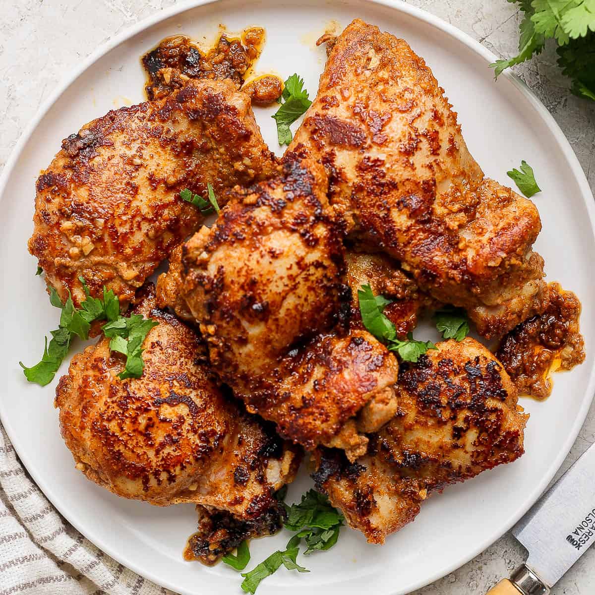 A plate filled with chicken shawarma chicken thighs and fresh parsley.