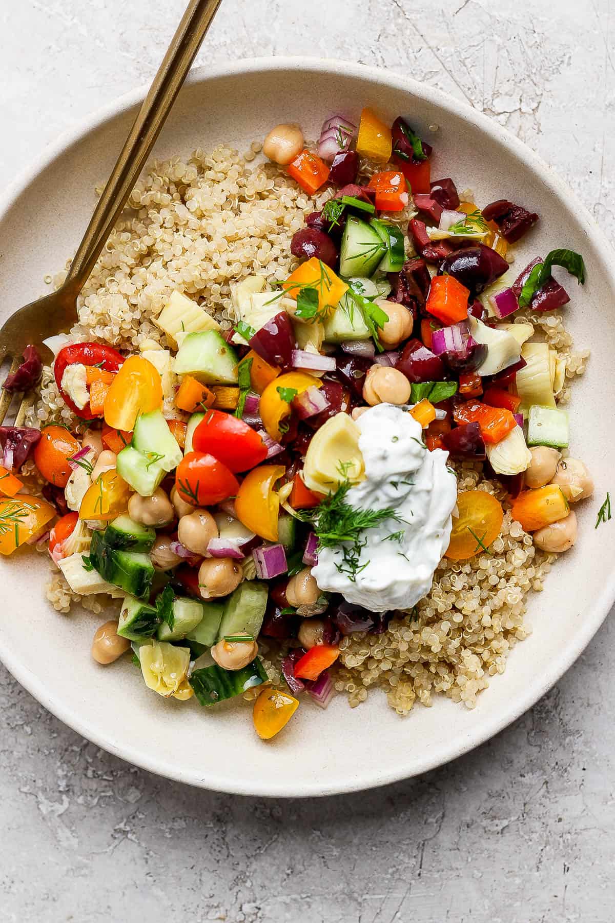 A large bowl of chickpea salad with quinoa and tzatziki sauce.