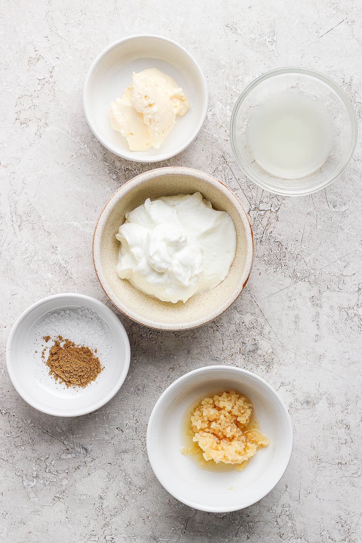 Ingredients for garlic white sauce in separate bowls.