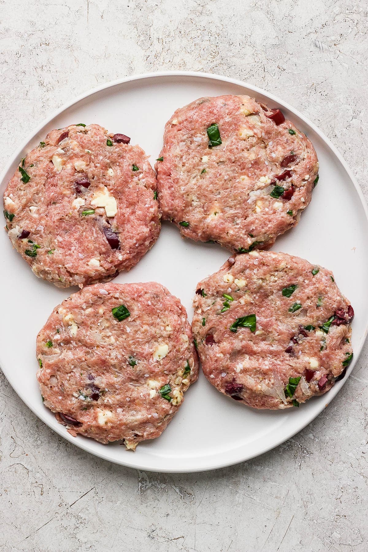 Greek turkey burgers with tzatziki sauce formed into 4 burger patties on a plate.