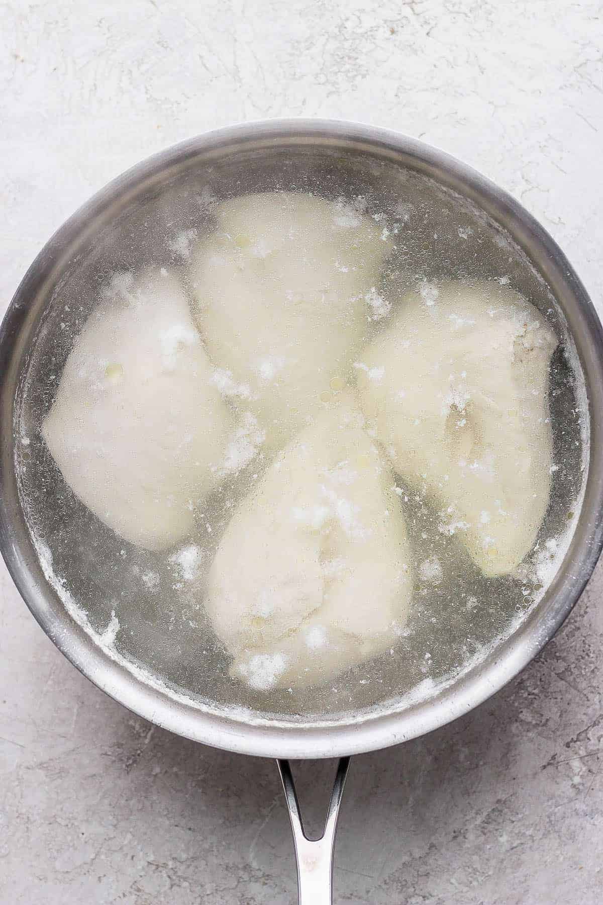 Four chicken breasts in a pot of boiling water to make shredded chicken for buffalo ranch chicken salad.