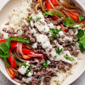 A philly cheesesteak rice bowl with ground beef, rice, cheese sauce and cooked onions and bell peppers.