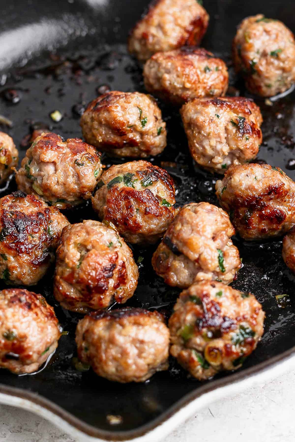 Cooked pork meatballs in a cast iron skillet. 