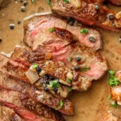 Sliced steak au poivre in a cast iron skillet.