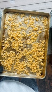 Someone holding a baking sheet of cooked crispy rice with an oven mitt.
