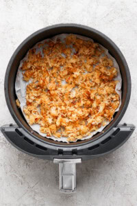 Cooked crispy rice in a parchment-lined air fryer.