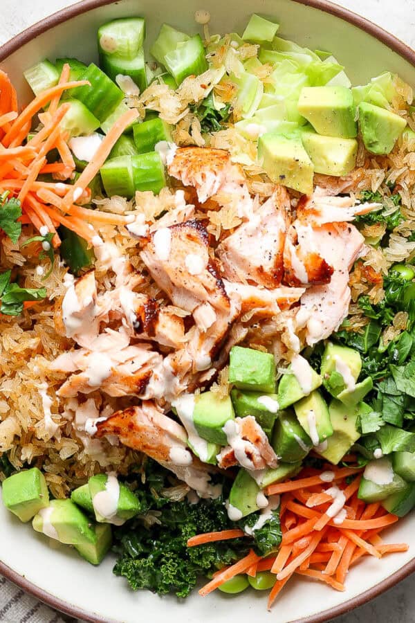 A big bowl of crispy rice salad with salmon, carrots, avocado, cucumber and cilantro.