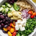 Bowl of greek quinoa salad in a bowl with ingredients separated out.