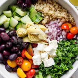 Bowl of greek quinoa salad in a bowl with ingredients separated out.