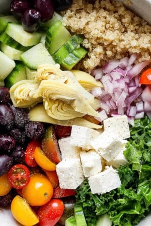 Bowl of greek quinoa salad in a bowl with ingredients separated out.
