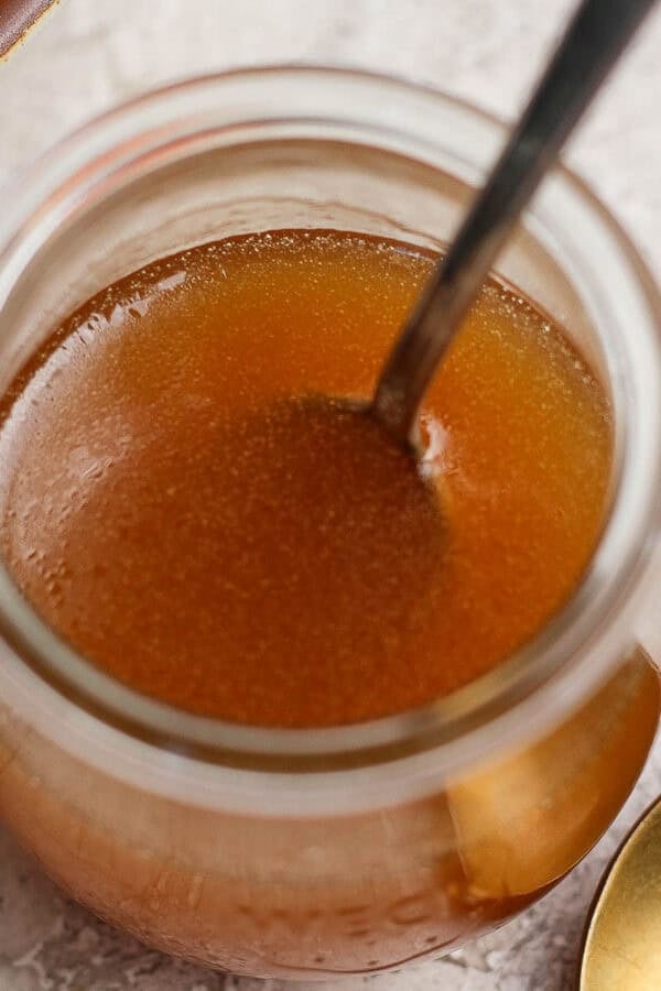 A jar of homemade honey vinaigrette with a spoon sticking out.