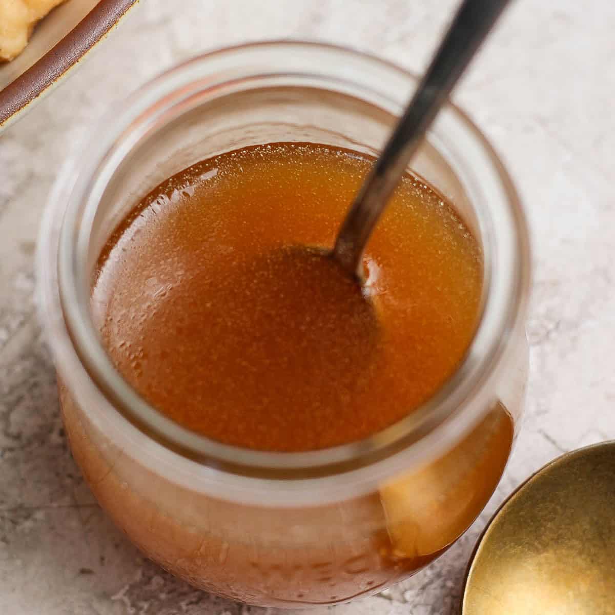 A jar of homemade honey vinaigrette with a spoon sticking out.
