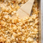 Crispy rice on a baking sheet with a wooden spatula sticking out.