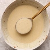 A bowl of lemon beurre blanc sauce with a spoon lifting some out.