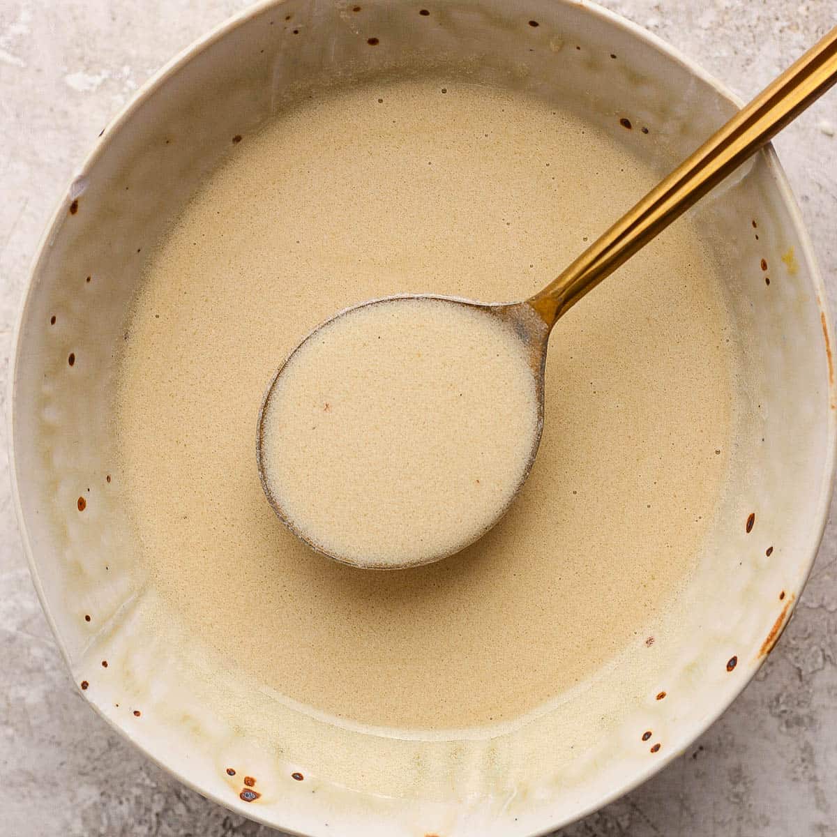 A bowl of lemon beurre blanc sauce with a spoon lifting some out.