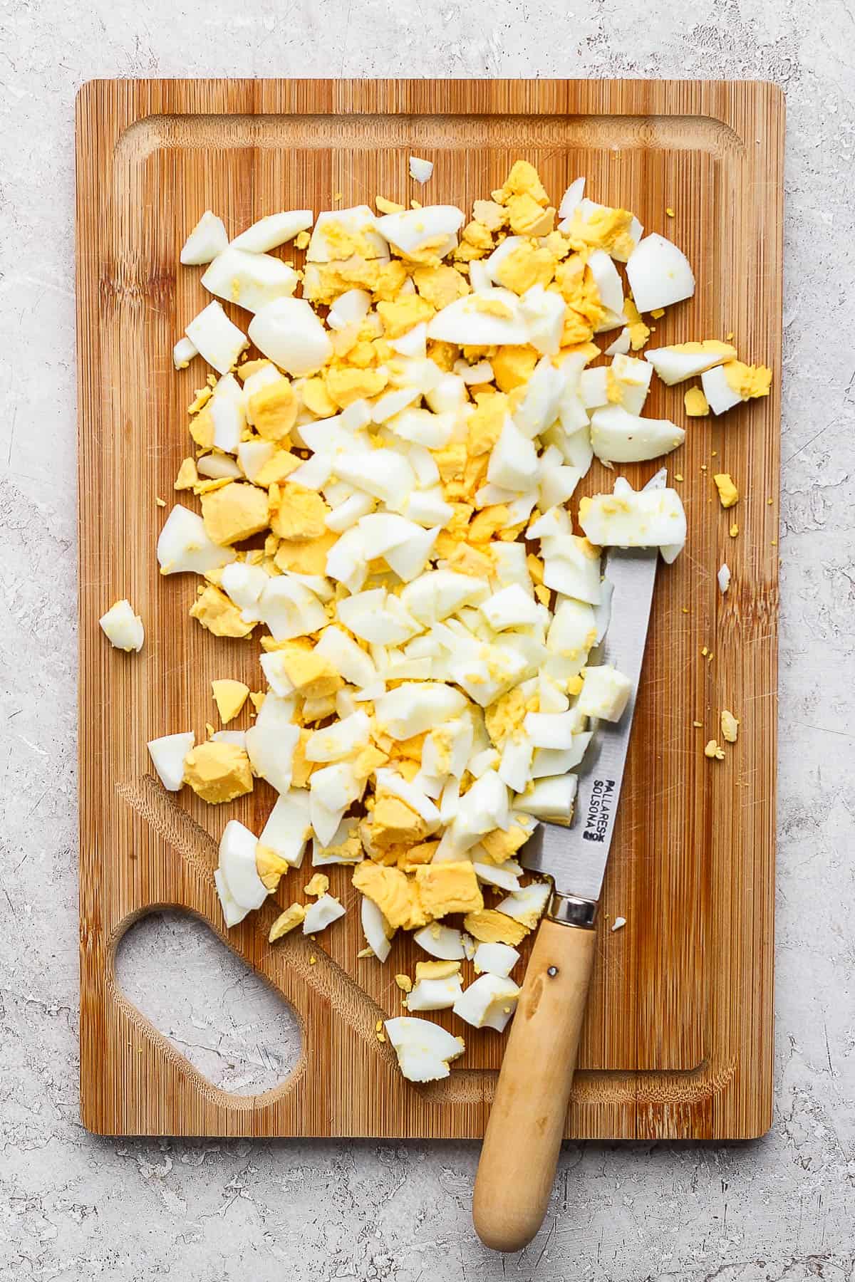 Hard boiled eggs chopped on a cutting board to make dill pickle egg salad.