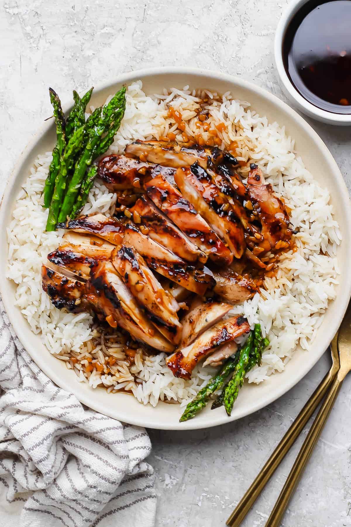 Bourbon chicken on a plate with rice and asparagus.
