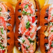 Close up top shot of a grilled crab roll with a top cut hot dog bun with grill marks and stuffed with grilled crab meat.