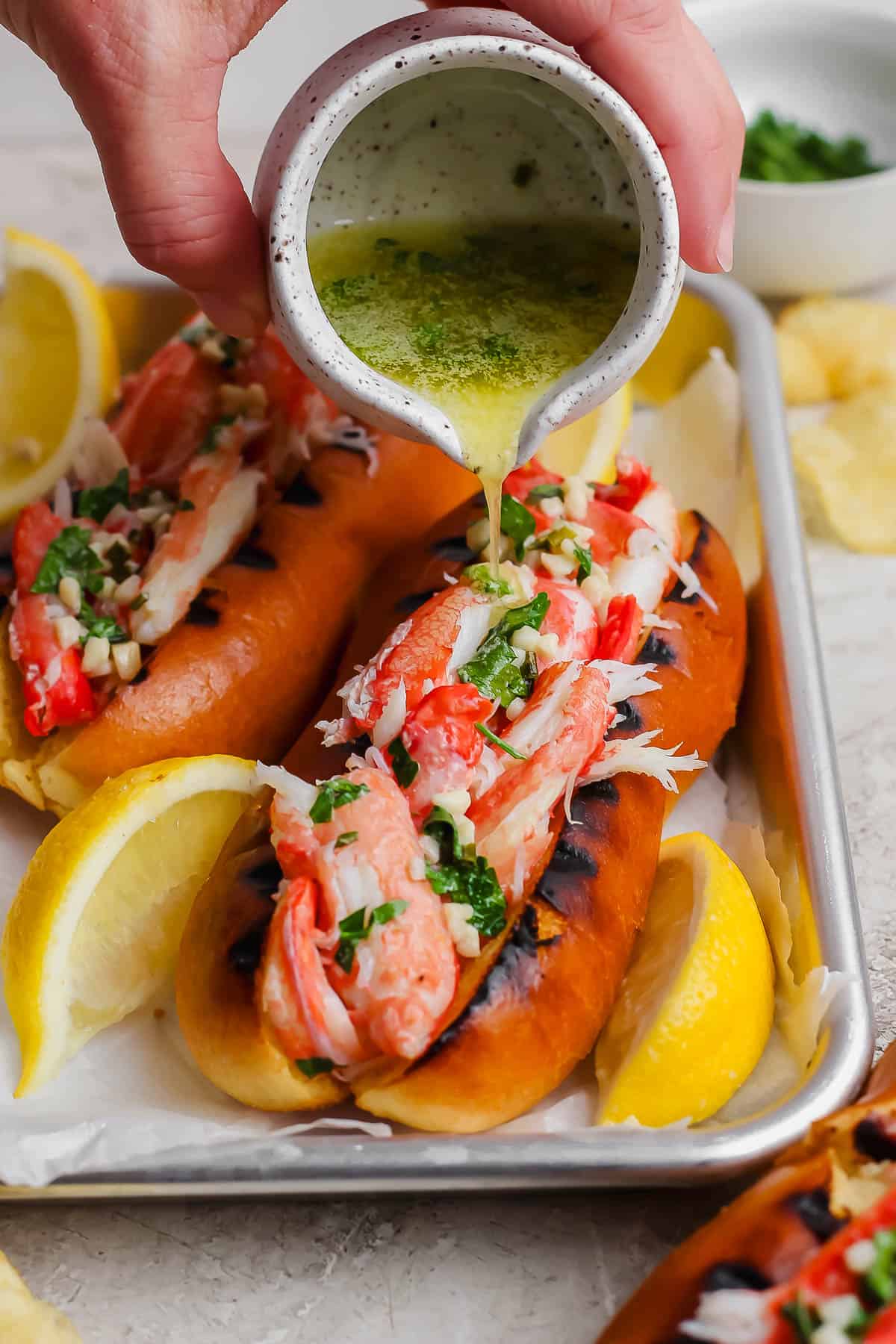 A fully assembled crab roll with the butter mixture being poured on top.