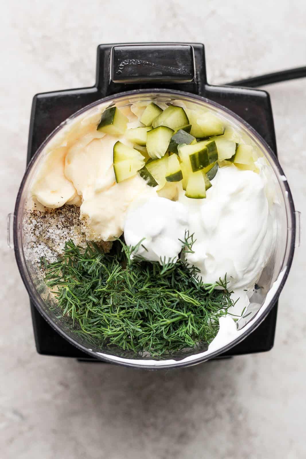 Dill pickle ranch dressing ingredients in a food processor unblended.