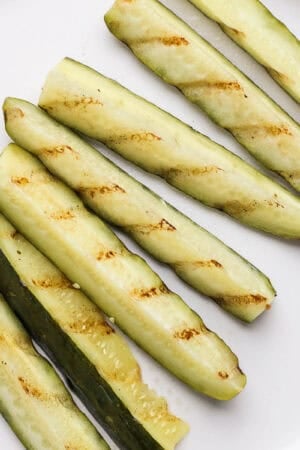 A plate of grilled pickles with grill marks.