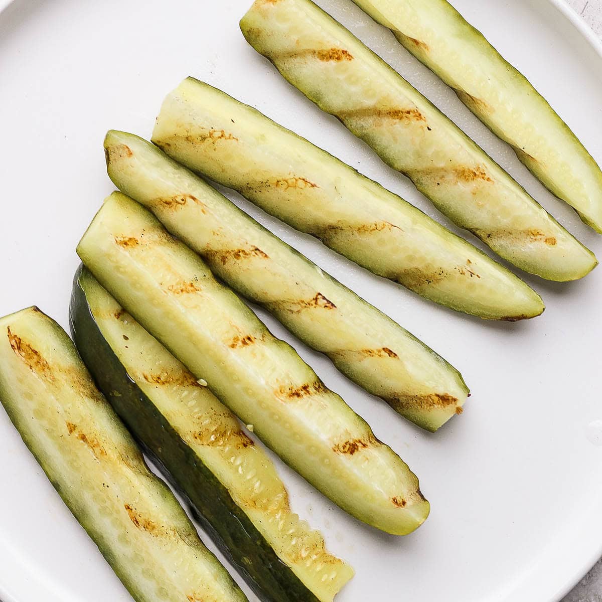 A plate of grilled pickles with grill marks.