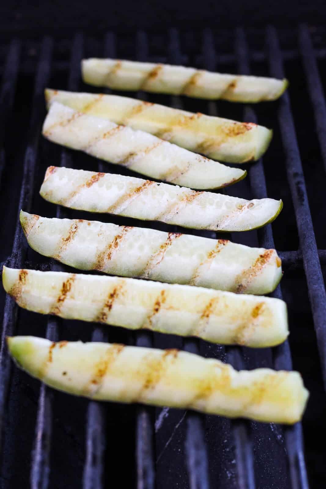 Pickle spears on the grill with grill marks.